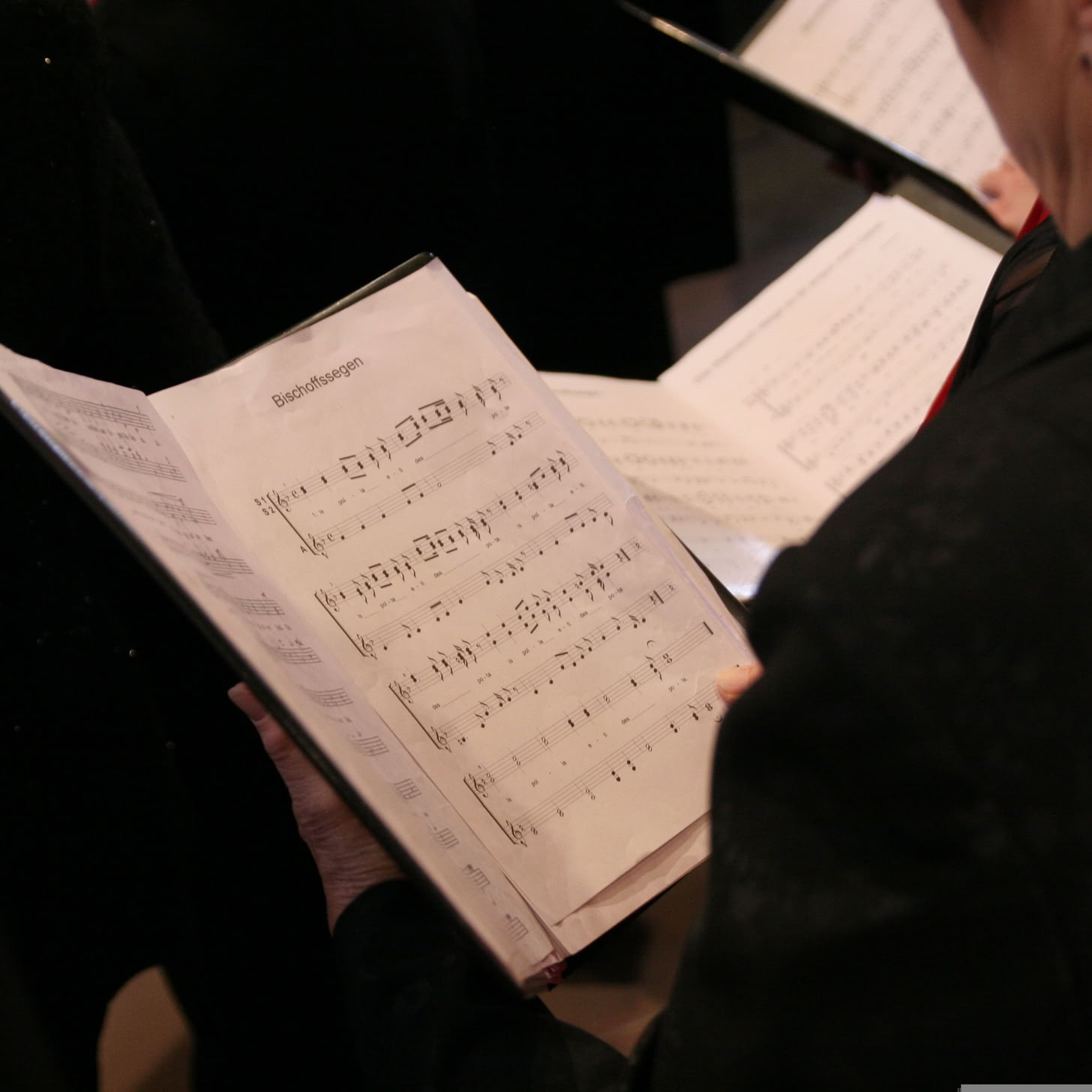 Ein Chor probt drinnen und konzentriert sich auf die Notenblätter für die Aufführungsübung.